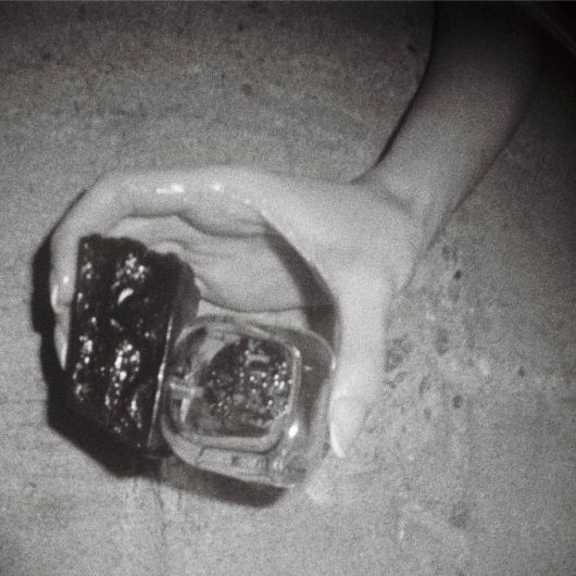 Hand on floor near perfume bottle